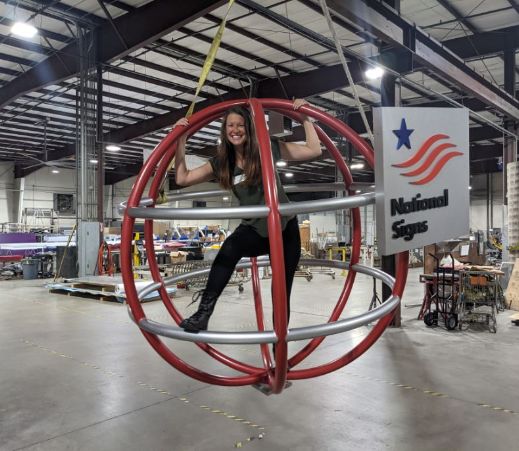 Katherine Garrett, one of our sales consultants, enjoys a spin in the National Signs globe!
