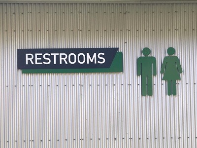 Restroom wayfinding signs on a metal wall