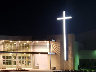 Stunning and large lighted church sign of a cross shining bright at night.