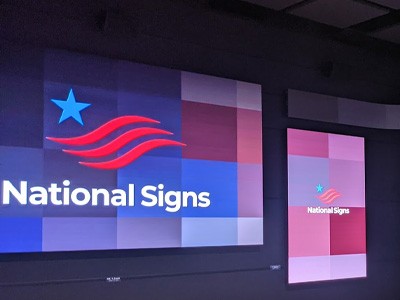Indoor Daktronics digital signs featuring the National Signs logo and color scheme.