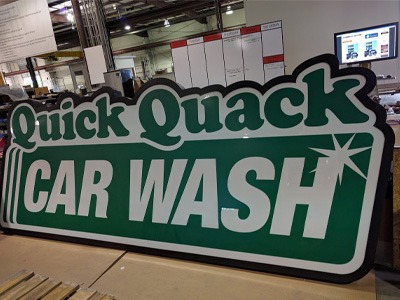 Back-lit sign for Quick Quack Car Wash sitting in the National Signs shop in Houston, Texas.