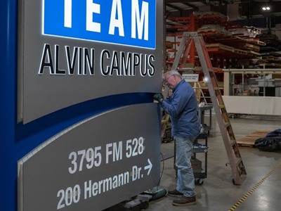Employee putting finishing touches on the TEAM school monument sign.